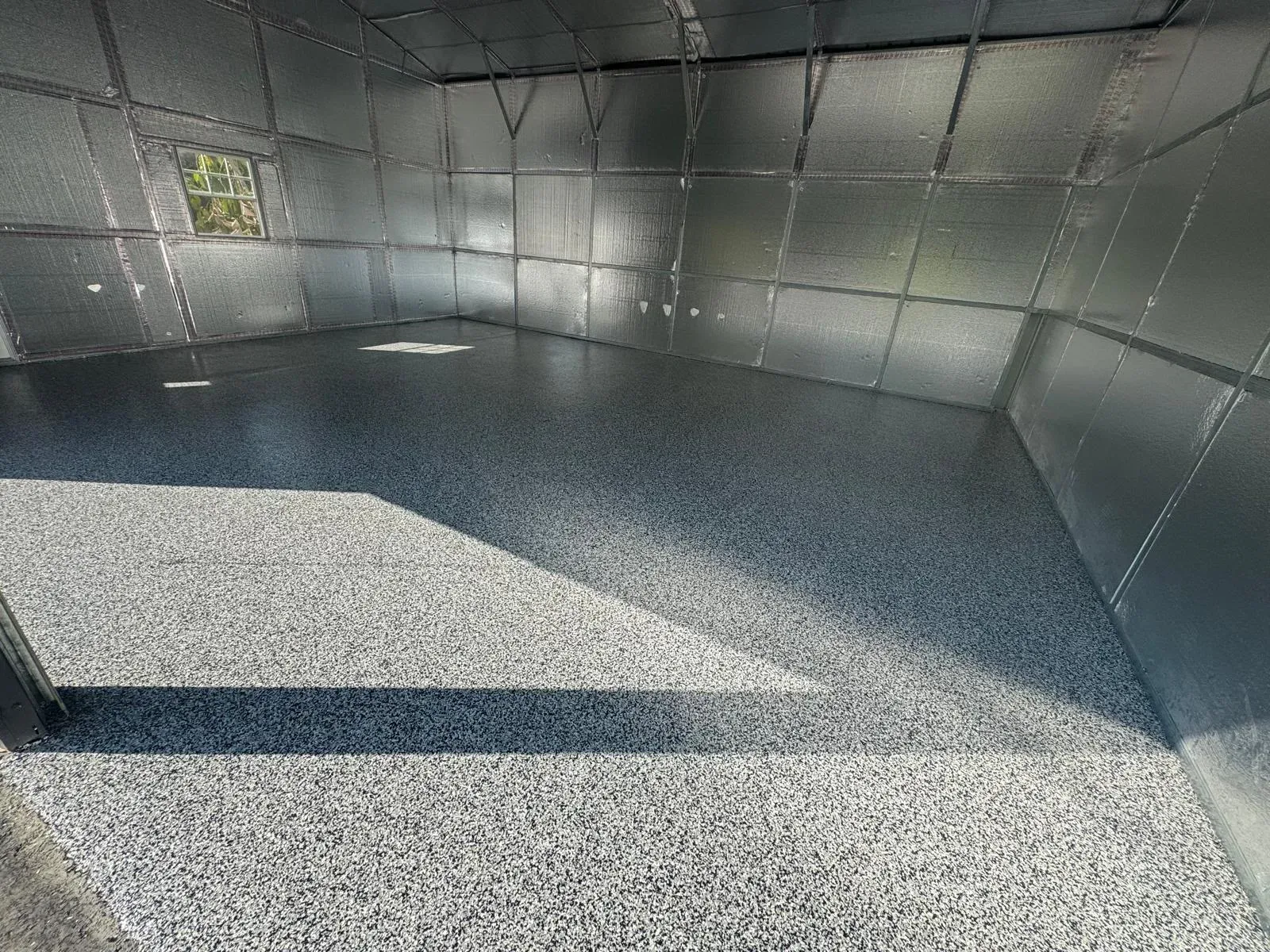 Three-car garage with gray flake epoxy floor and metal walls